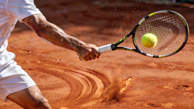 网球运动员在红土场上挥拍击球